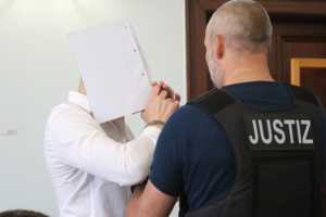 Angeklagter im Gerichtssaal, dem die Handfesseln abgenommen werden.