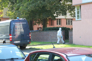 Mitarbeiter der Spurensicherung im Schutzanzug unweit des Wagens.