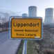 Ortsschild zu Lippendorf, Türme des Kraftwerks im Hintergrund.