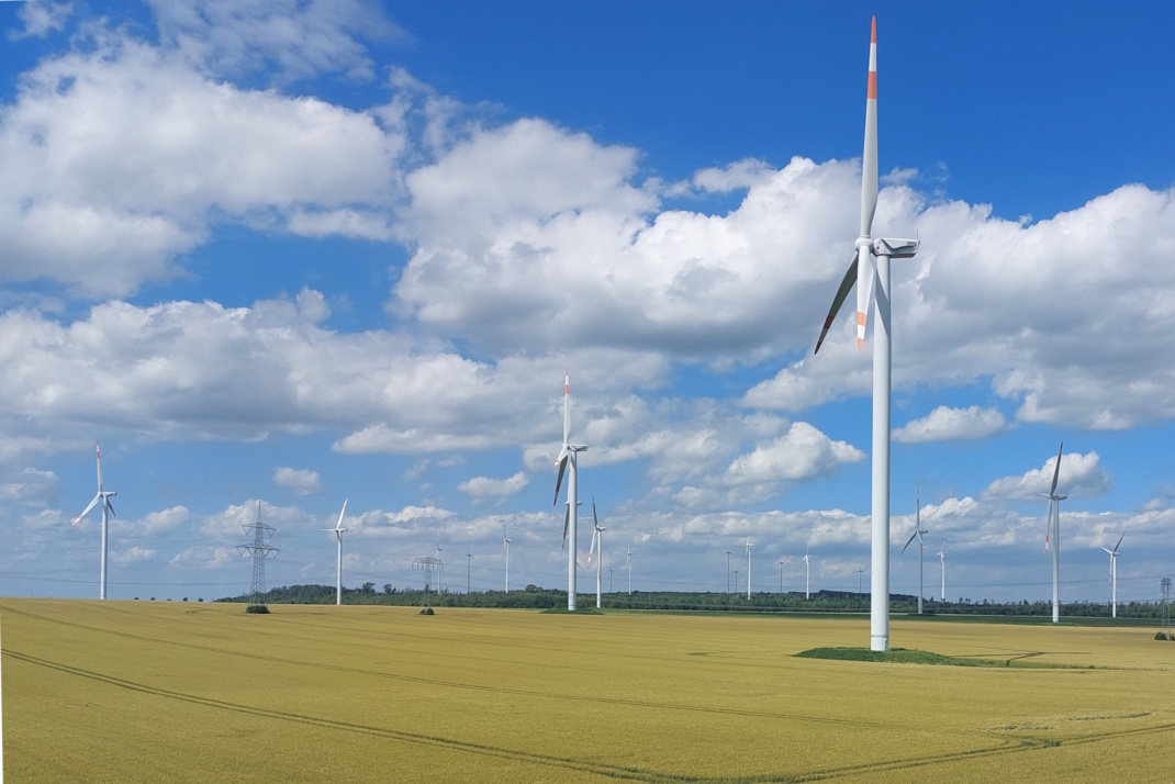 Windkraftanlagen auf freiem Feld, Wolken und blauer Himmel.