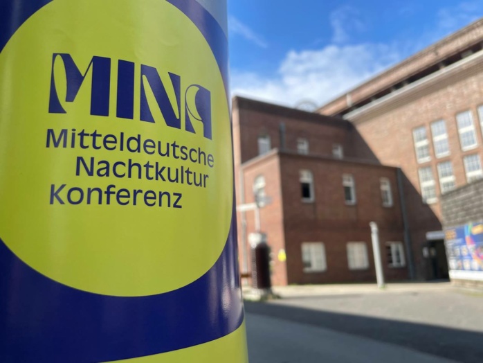 Aufkleber, im Hintergrund Backsteingebäude, blauer Himmel