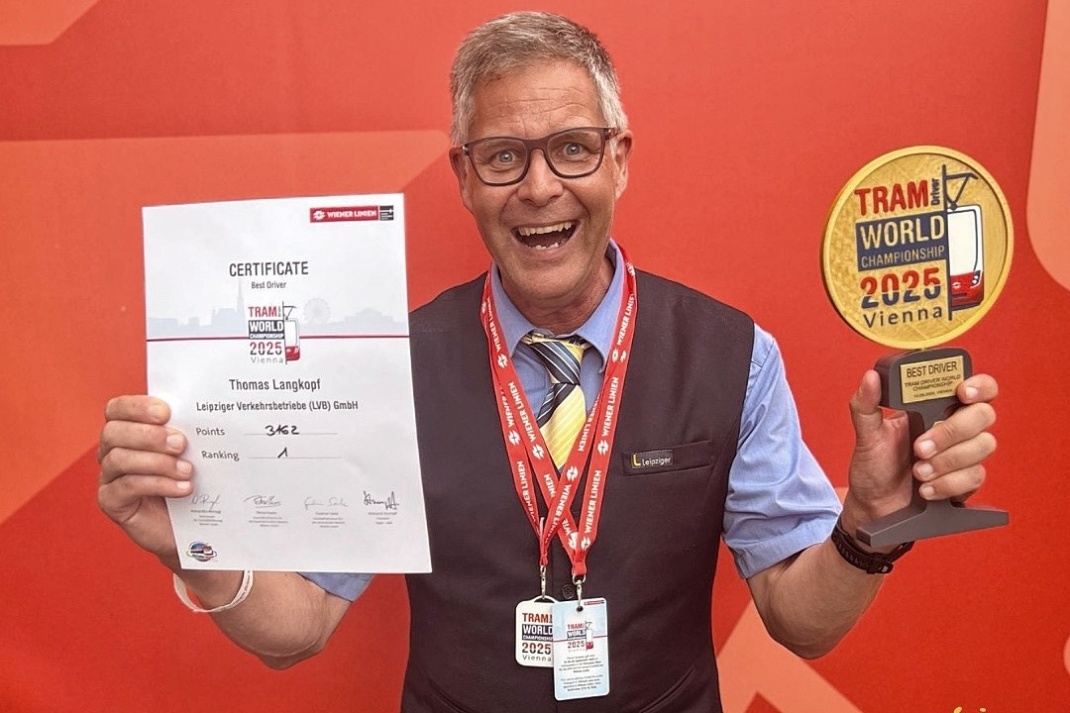 Mann hält freudestrahlend Urkunde und Pokal in die Kamera.