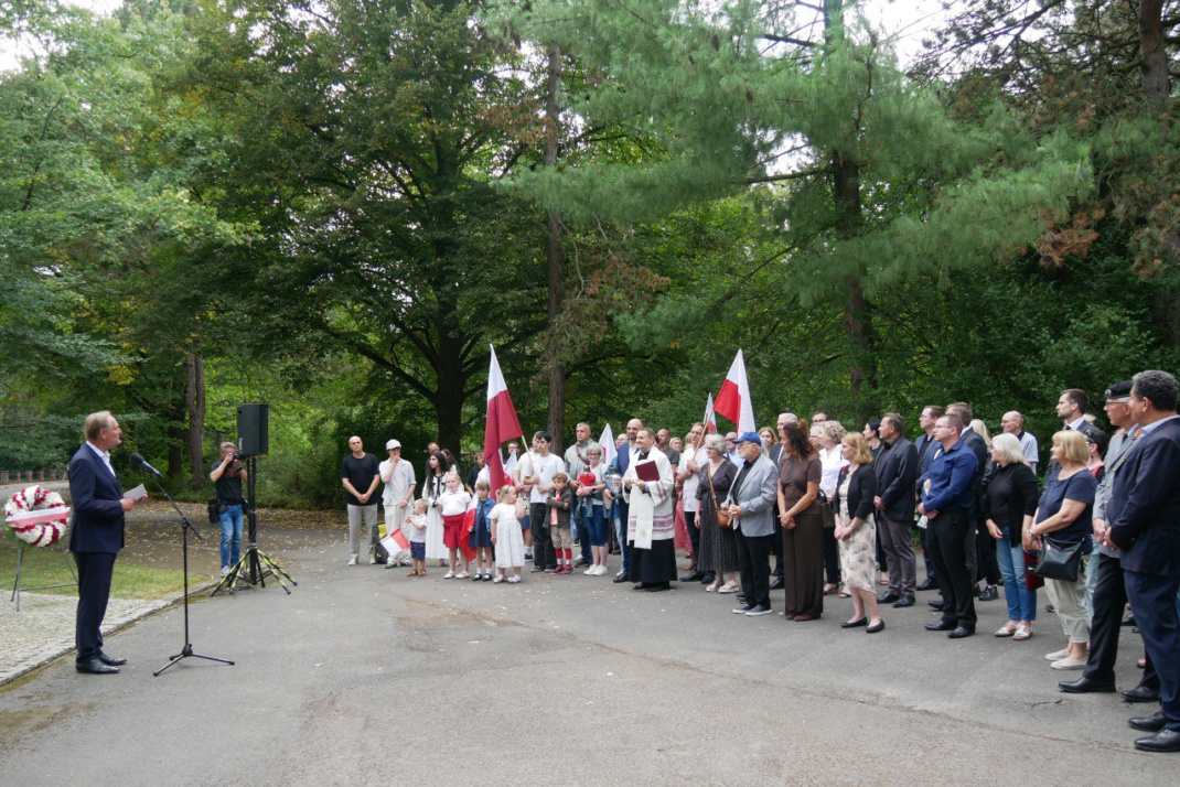 Gedenkveranstaltung mit einem Redner, dem viele Menschen gegenüberstehen.