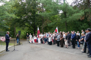 Gedenkveranstaltung mit einem Redner, dem viele Menschen gegenüberstehen.