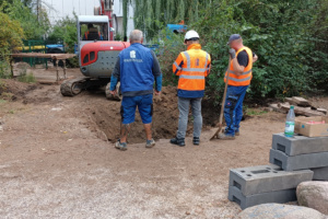 Arbeiter schaufeln Bereich mit Erde zu.