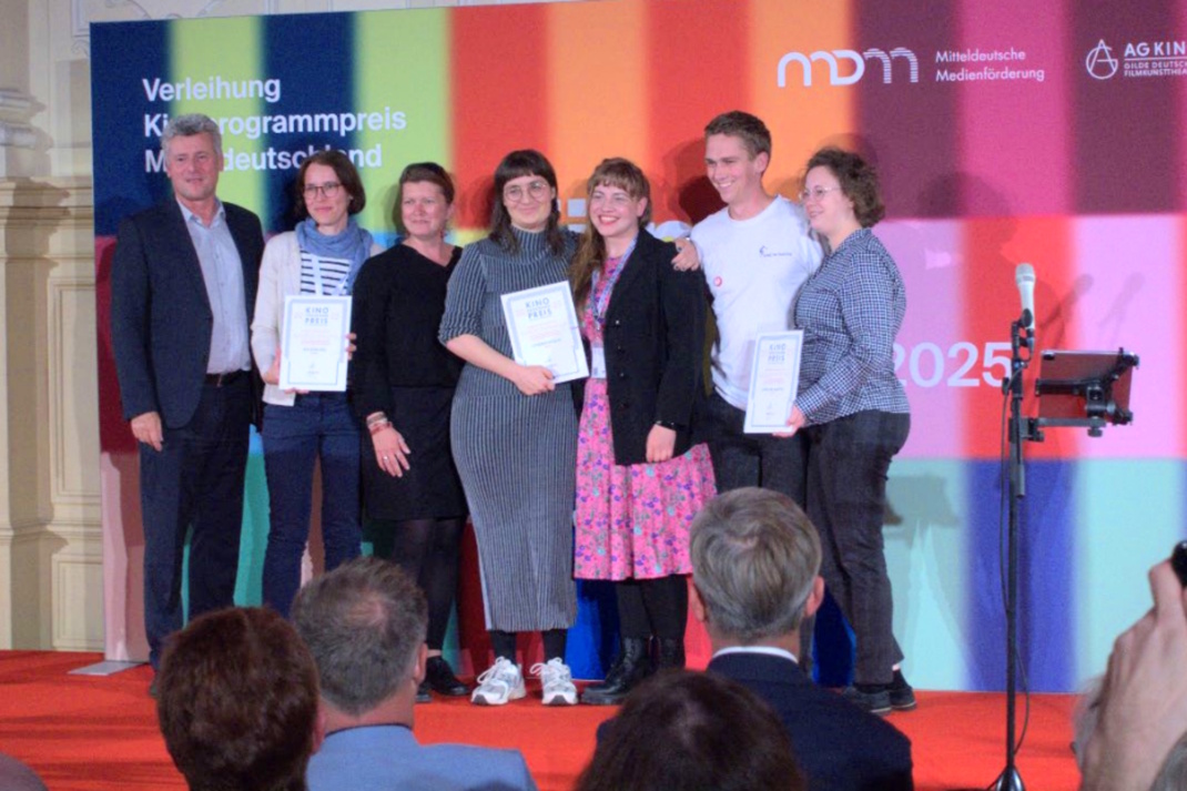 Personengruppe steht auf einer Bühne.