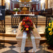 Sarg, der zur Trauerfeier in einer Kirche steht, mit Bildnis und Blumenschmuck.