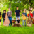 Gruppe junger Menschen mit Musikinstrumenten steht auf einer Wiese im Park.