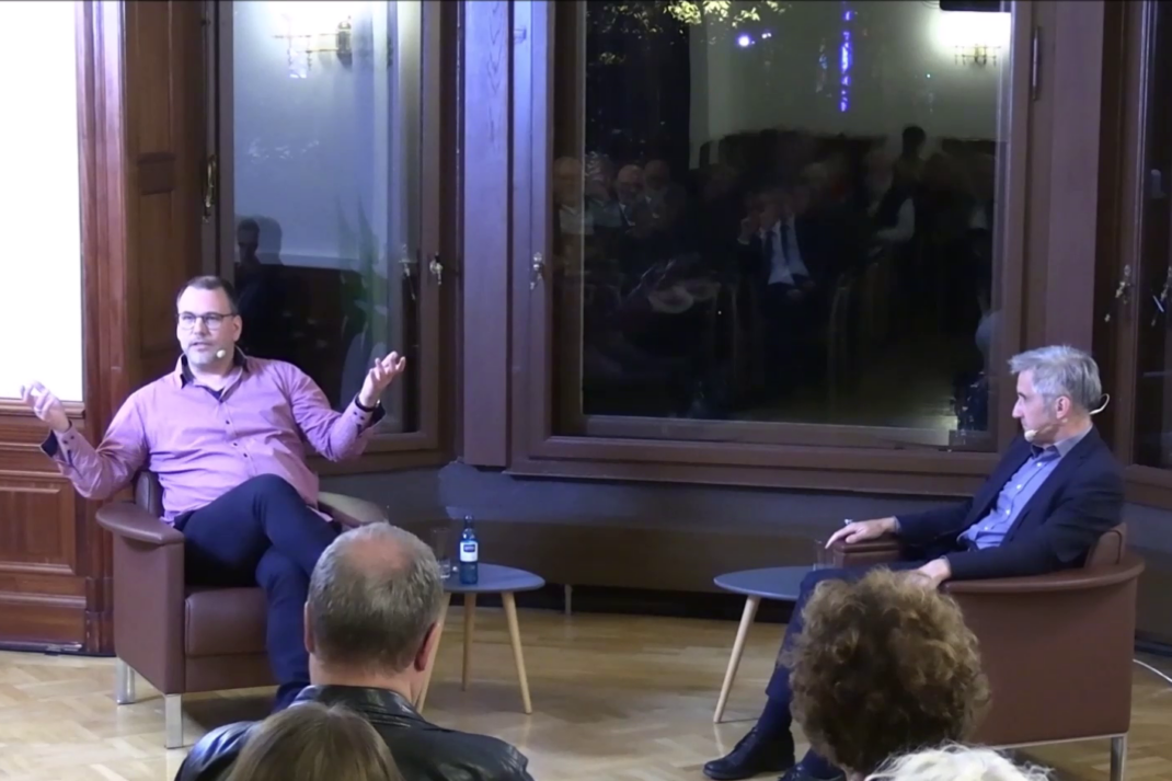 Zwei Personen sitzen auf Stühlen und diskutieren,