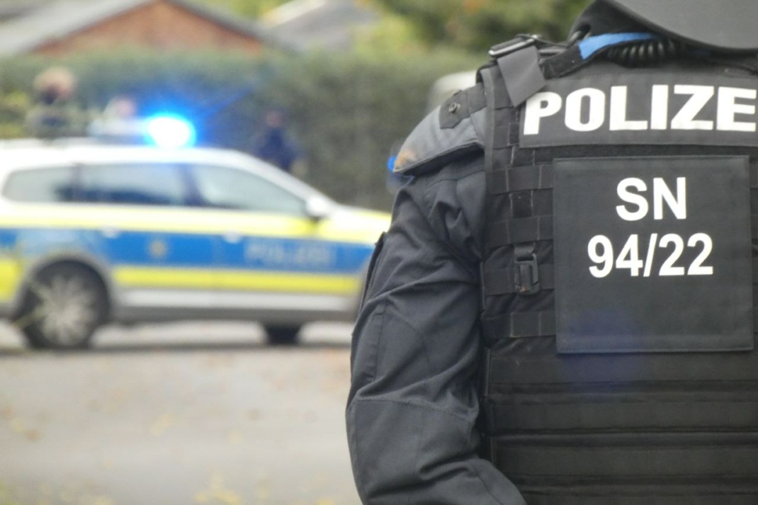 Ein Polizist vor einem Polizeiauto im Hintergrund