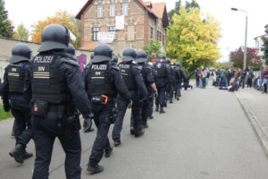 Polizeieinheiten gehen eine Straße entlang.