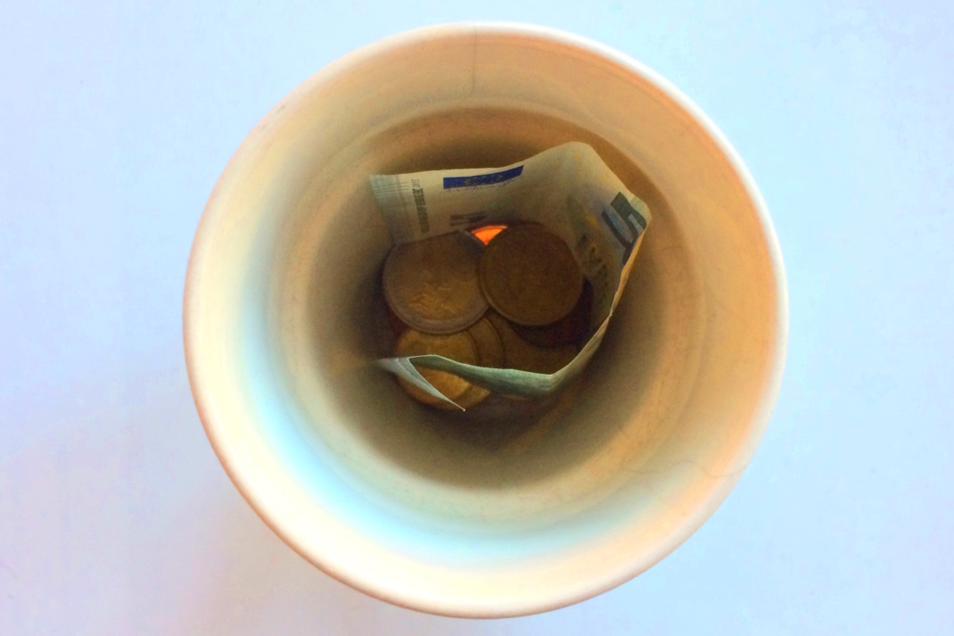 Mit Geld gefüllte Tasse von oben.