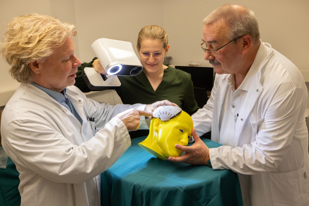 Prof. Dirk Winkler, Direktor der Klinik und Poliklinik für Neurochirurgie, Katharina Scheidt, wissenschaftliche Mitarbeiterin, und Oberarzt Dr. Christian König (v. l.) betrachten das zu untersuchende Schädelimplantat., Foto: UKL / Stefan Straube
