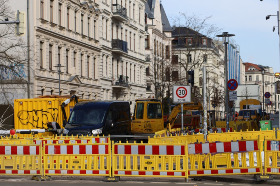 Baustelle im Wohngebiet mit Absperrung und Fahrzeugen.