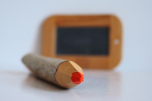 Buntstift in Nahaufnahme, dahinter eine Schreibtafel.