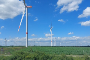 Windkraftanlagen bis zum Horizont auf einem Feld, Wolken und blauer Himmel.