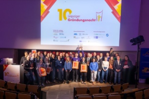 Gruppenbild auf Bühne und mit Bildschirm.