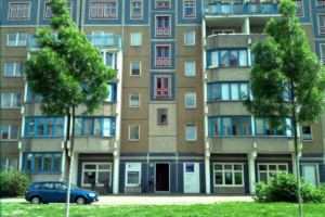 Hausfassade mit Bäumen und Wiese.