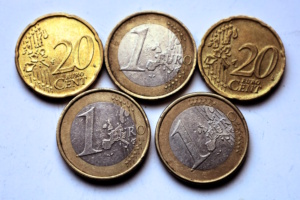 Aufgereihte Euromünzen liegen in zwei Reihen AUF heller Fläche.
