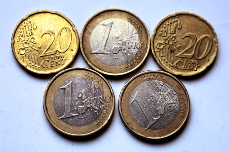 Aufgereihte Euromünzen liegen in zwei Reihen auf heller Fläche.