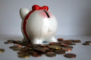 Helles Sparschwein, daneben liegen Münzen verstreut-