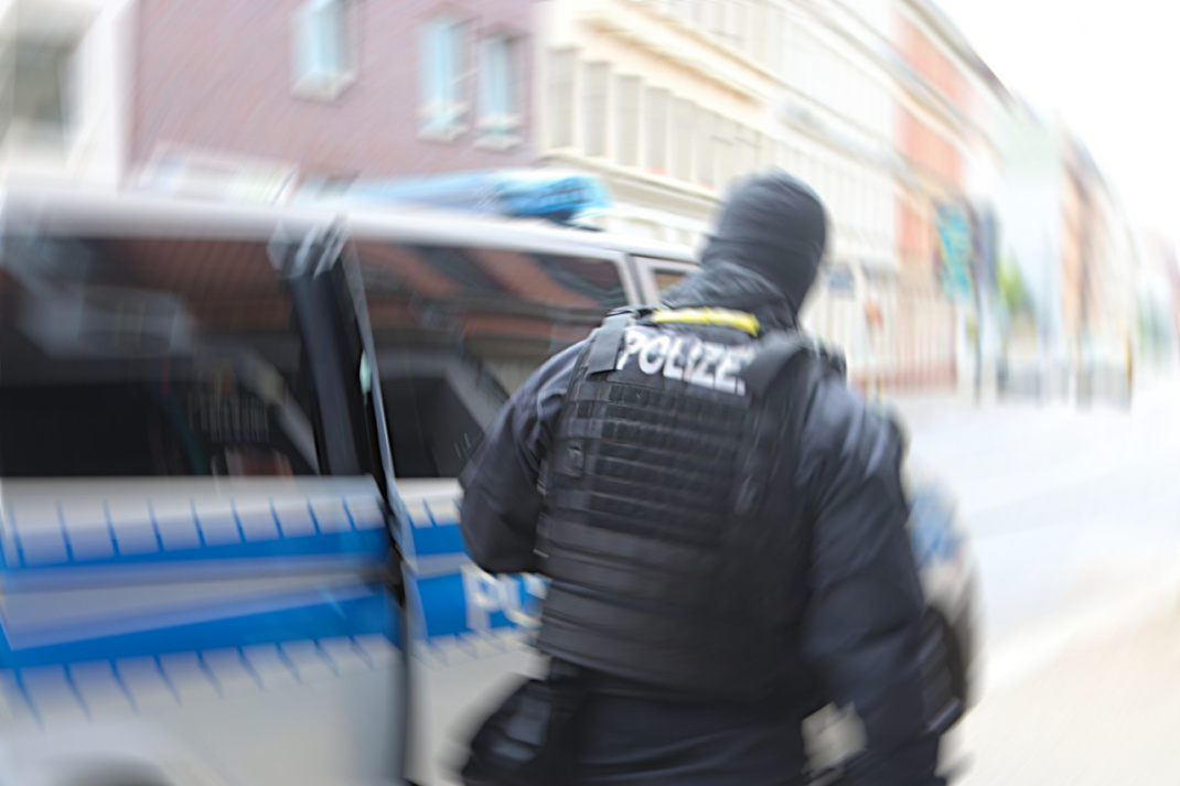 Vermummter Polizist an Polizeiwagen,