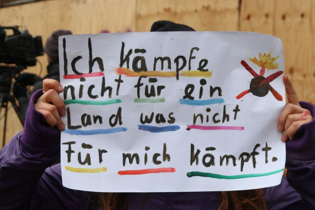 Plakat wird in die Kamera gehalten.