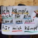 Plakat wird in die Kamera gehalten.