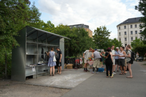 Menschen stehen neben einer Tauschbox.