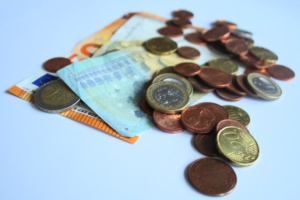 Euromünzen und Euroscheine liegen ungeordnet auf einer Fläche.