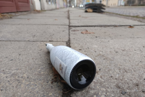 Weiße Flasche liegt auf dem Gehsteig.