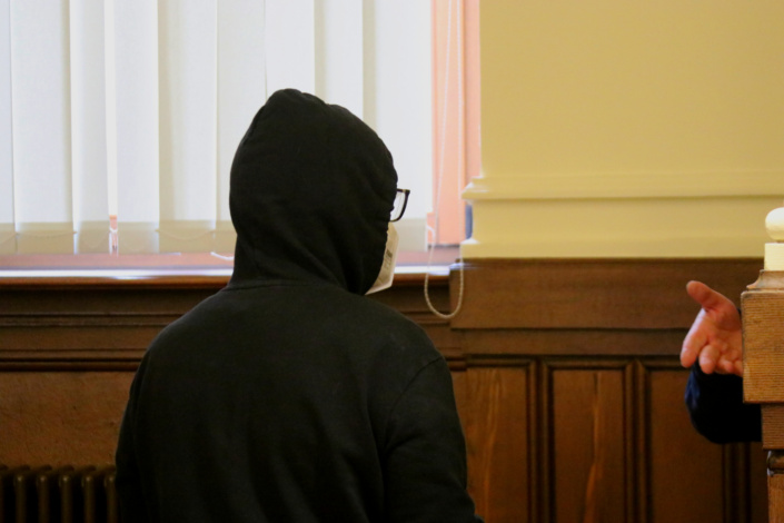 Angeklagter steht mit Kapuze im Gerichtssaal.