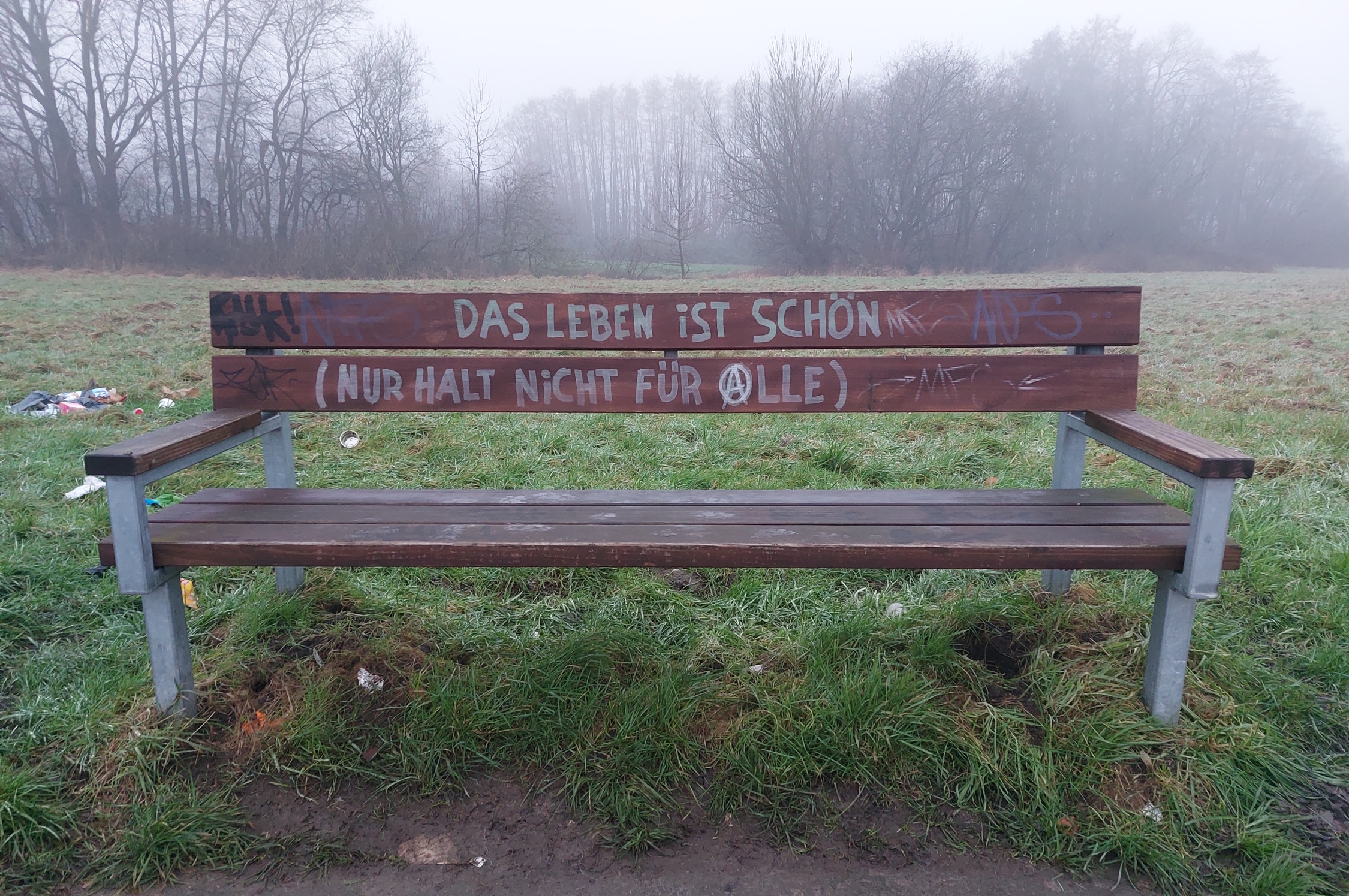 Beschriftete Sitzbank in der Landschaft.