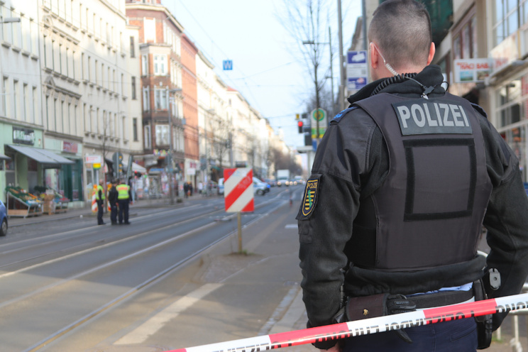 Polizeibeamter von hinten an einem Absperrband.