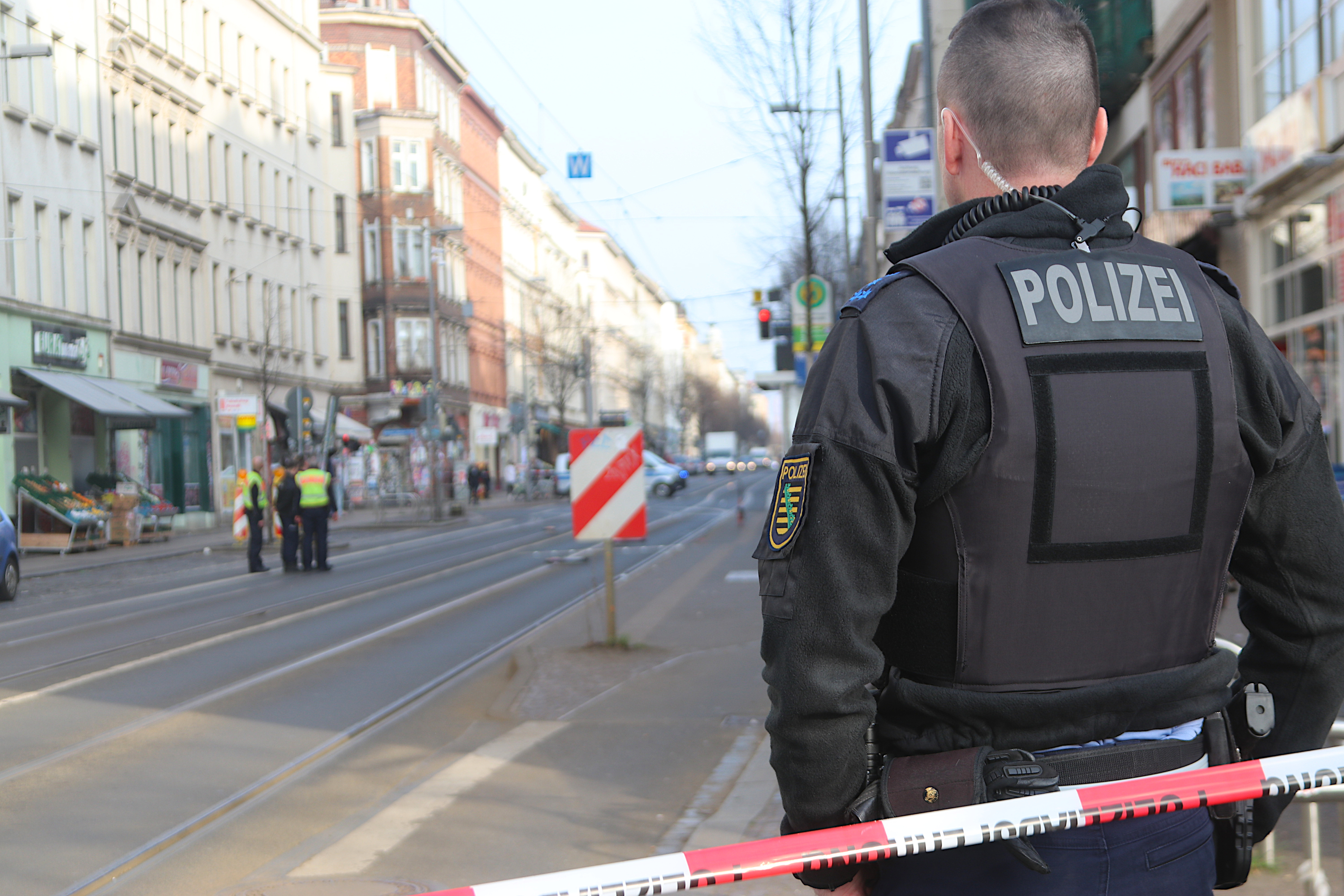 Polizeibeamter von hinten an einem Absperrband.