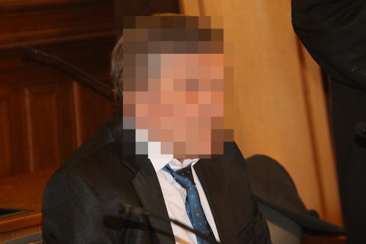 Angeklagter im Anzug, Gesicht verpixelt.