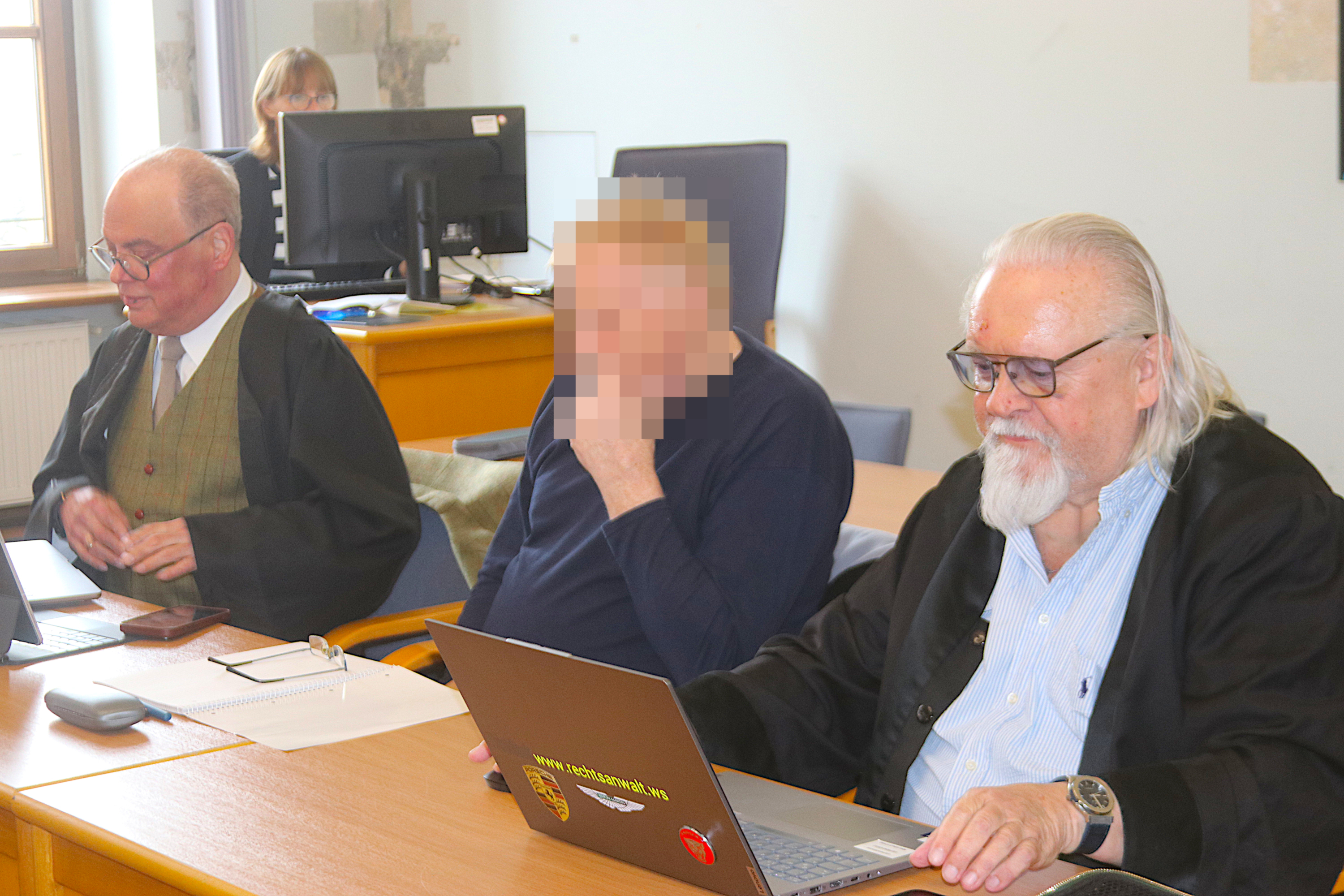 Angeklagter sitzt zwischen Verteidigern am Gericht.