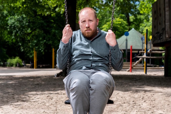 Mann sitzt auf Schaukel.