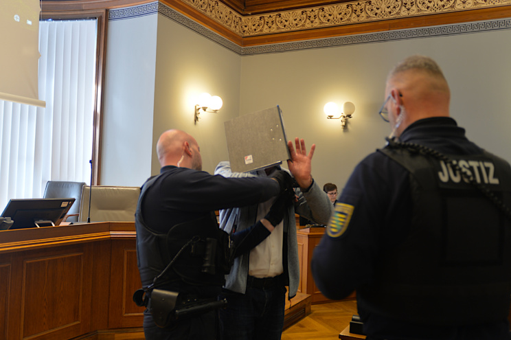 Justizbeamte nehmen Angeklagtem Handfesseln ab.