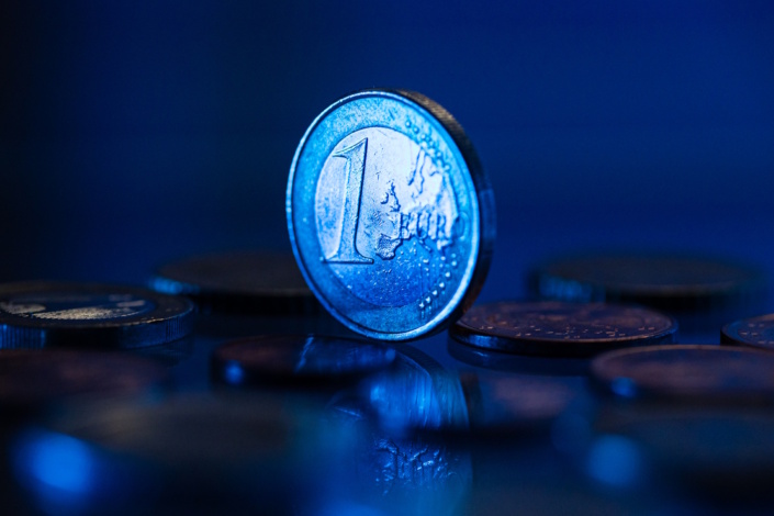 Eurostück steht symbolisch in blauem Licht.