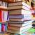 Gestapelte Bücher, im Hintergrund volle Regale.