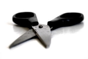 Schere mit schwarzen Griffen vor weißem Hintergrund.