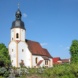 Helles Kirchengebäude vor blauem Himmel.