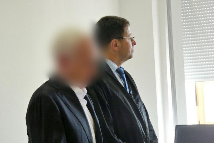 Prof. Strauß steht neben seinem Verteidiger als Angeklagter im Gerichtssaal.